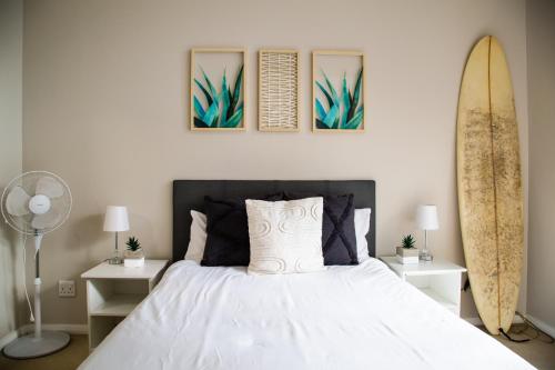 a bedroom with a bed and a surfboard on the wall at Spacious Surfers Corner Beach Apartment in Cape Town