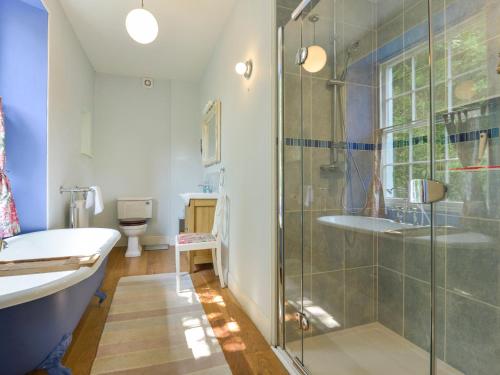 a bathroom with a shower and a tub and a sink at Woodlands in Dartmouth