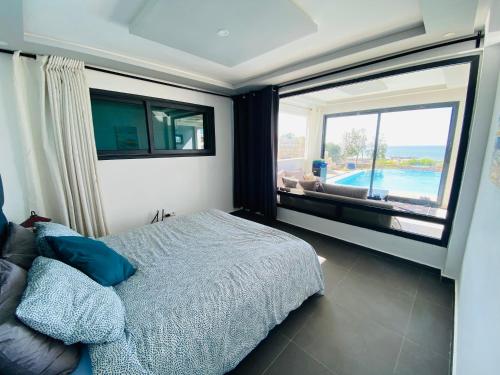 a bedroom with a bed and a large window at LES OLIVIERS Villa N2 avec piscine privée in Oualidia