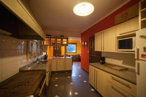 a kitchen with white cabinets and a red wall at Boutique Hotel Sevilla in La Cumbre