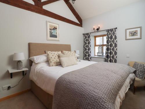 a bedroom with a large bed and a window at 1 Walkers Barn in Settle