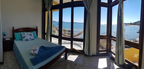 een slaapkamer met een bed en uitzicht op de oceaan bij Pousada Pedra das Tartarugas in São Francisco do Sul