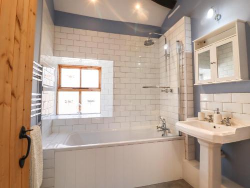 a white bathroom with a tub and a sink at 1 Walkers Barn in Settle