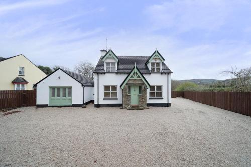 a white house with a green door on a driveway at Spacious Coastal Accommodation with Games Room - Sleeps 10 in Rathmullan