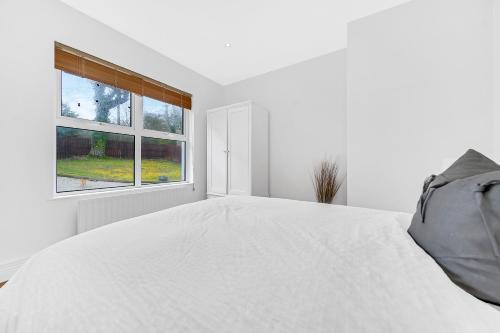 a white bedroom with a large bed and a window at Spacious Coastal Accommodation with Games Room - Sleeps 10 in Rathmullan