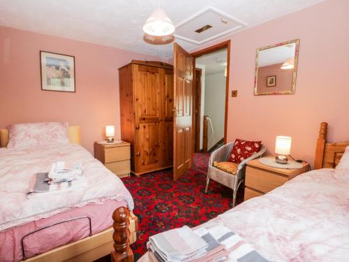 een slaapkamer met 2 bedden en een stoel bij Rose Cottage in Kendal