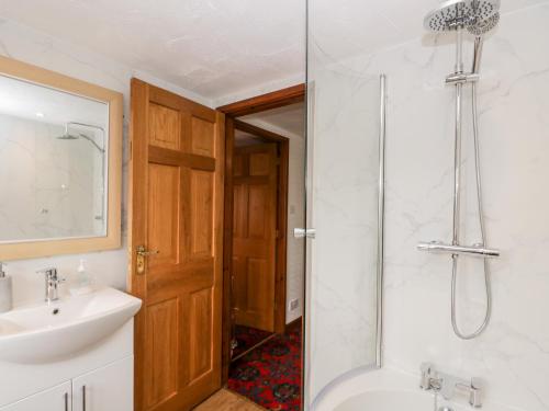 een badkamer met een bad, een wastafel en een douche bij Rose Cottage in Kendal