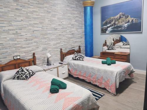 a bedroom with two beds and a brick wall at Centro de Baracaldo, parcela de garaje gratis in Barakaldo