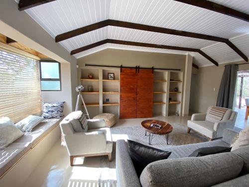 een woonkamer met een bank, stoelen en een tafel bij Ostrich Hide in Marloth Park