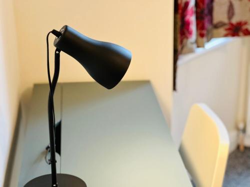 a black lamp sitting on top of a desk at Nice and Pleasant in Thornton Heath