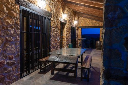 un patio amurallado de piedra con mesa de cristal y bancos en Casas Rurales Las Cuevas El Rincón, en Fuentes de León