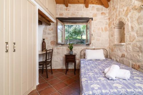 a bedroom with a bed and a table and a window at Strofilia Authentic Villas in Skinária