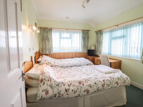 een slaapkamer met 2 bedden en 2 ramen bij Morlyn Guest House Apartment in Harlech