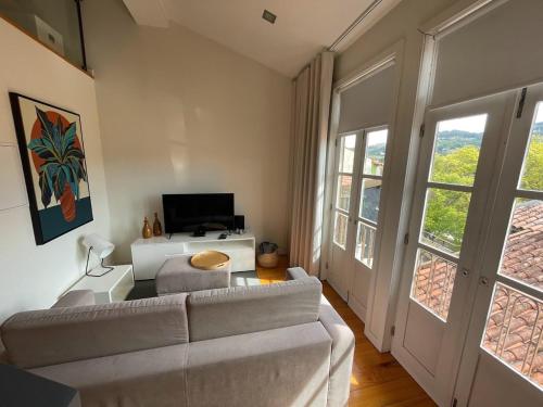 a living room with a couch and a tv at Mezzanine Apartment in Guimarães