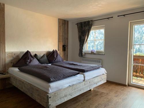 a bed in a room with two windows at Ferienhof-Oberer-Gollmitzer-2-5-km-oberhalb-von-Heiligenblut-ruhige-sonnige-Lage-Glocknerblick in Heiligenblut