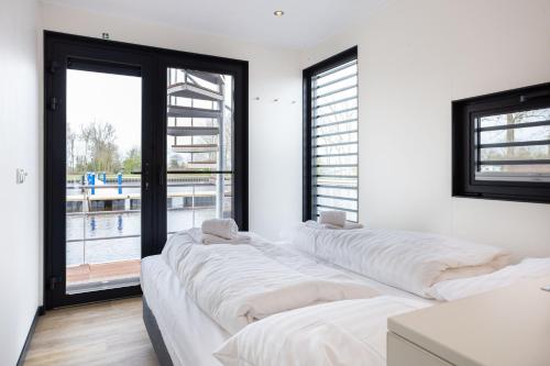 Habitación con 3 camas blancas y ventana. en Houseboat 'de Valreep' met tuin - Sneek - Offingawier, en Offingawier