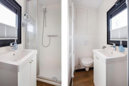 een witte badkamer met een wastafel en een douche bij Houseboat Agua Dolce met tuin, Paviljoenwei 4, Sneek - Offingawier in Offingawier