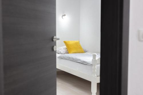 a room with a bed with a yellow pillow on it at Apartments Luka in Senj