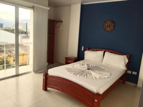 a bedroom with a bed with a blue wall at Hotel Villareal del Llano in Villavicencio