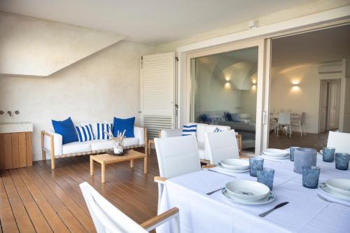 una sala da pranzo con tavoli bianchi e sedie blu di Sardinia Gold Luxury Apartment a Palau