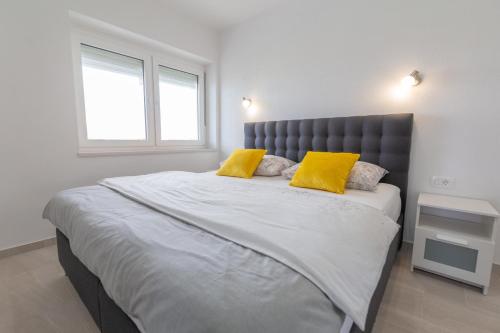 a bedroom with a large bed with two yellow pillows at Apartments Luka in Senj