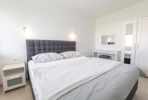 a white bedroom with a large bed with two pillows at Apartments Luka in Senj