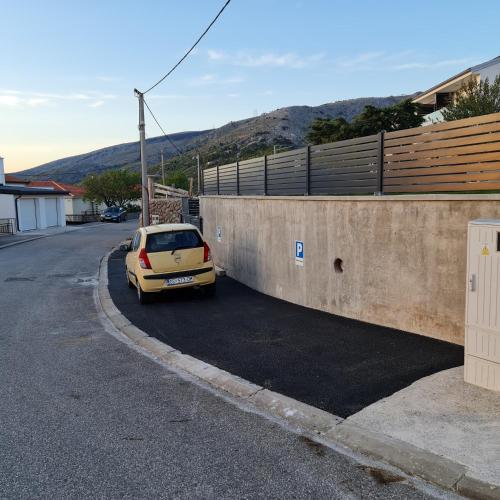 a yellow car parked in a parking lot next to a wall at Apartments Luka in Senj