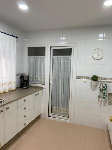 a kitchen with white cabinets and a clock on the wall at Apartamento Tía Maria in Cádiz