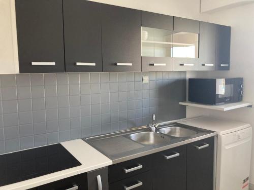 une cuisine avec un évier et un micro-ondes dans l'établissement Appartement 6 places à 200m de l'océan, à La Rochelle