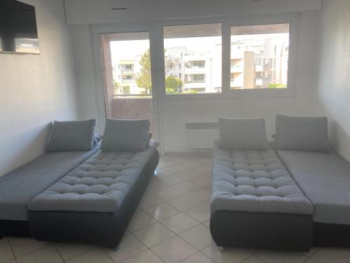 - un salon avec deux canapés et deux fenêtres dans l'établissement Appartement 6 places à 200m de l'océan, à La Rochelle