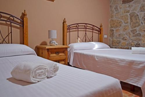 a bedroom with two beds with white sheets at La Casa de Irene in Lubián