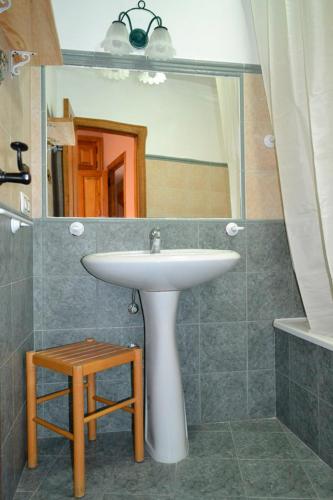 a bathroom with a sink and a mirror and a stool at Hotel Rural La Casa de Irene in Lubián