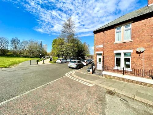 a brick building with cars parked next to a street at Huge serviced Apartment with FREE PARKING in Jesmond