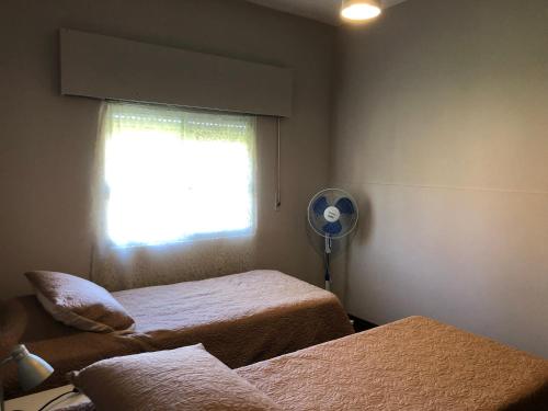 1 dormitorio con 2 camas y ventana con ventilador en Casa en el Real de san carlos en Colonia del Sacramento