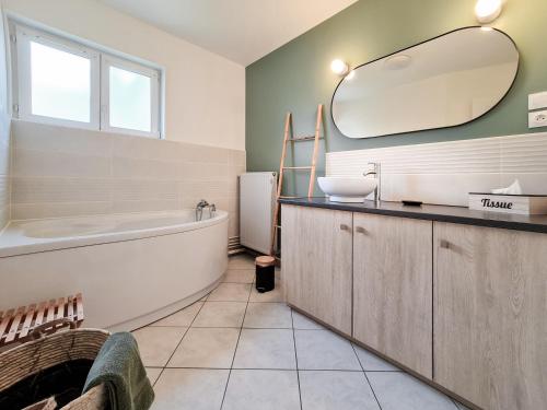 a bathroom with a tub and a sink and a mirror at Gîte du Vieux Château in Carvin