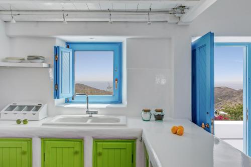 a kitchen with green cabinets and a sink and two windows at Illusion Villa - Exceptional Private Villa in Akrotiri