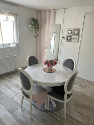 une table blanche avec des chaises et un vase de fleurs. dans l'établissement Chambre celia lits séparés, à Dieppe
