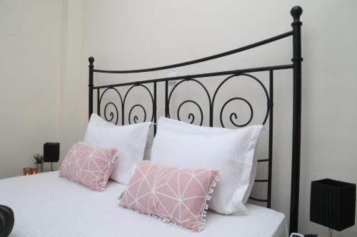 a black and white bed with pink pillows at CozyLuxuryApartment in Keramoti