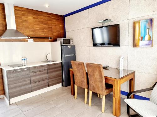 a kitchen with a table with chairs and a refrigerator at Apartamentos El Arrecife in Conil de la Frontera