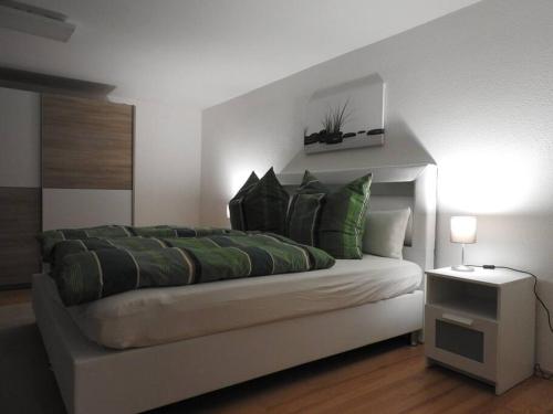 um quarto com uma cama grande e almofadas verdes em Schöne gemütliche Ferienwohnung mit Fernblick. em Nalbach