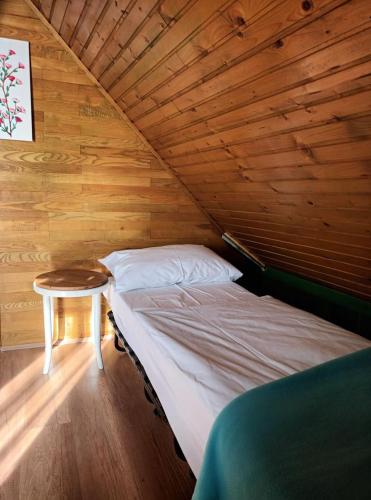 a bed in a wooden room with a table at Robinson Vila Kitokret in Kutjevo