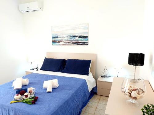 a bedroom with a blue bed with towels on it at CapoSud - Appartamento Giglio in Punta Secca
