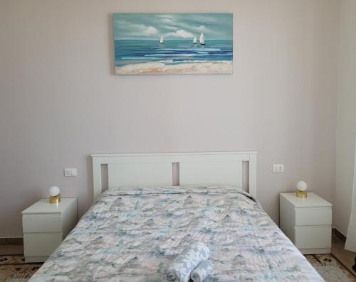a white bedroom with a bed and two night stands at Sea view in Lerici