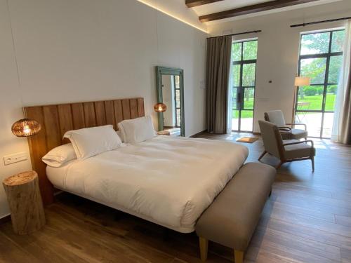een slaapkamer met een groot wit bed en een stoel bij HOTEL MAS ARET in Peralada