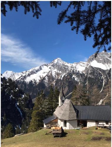 a church on a hill with a snow covered mountain at Haus Gletscherblick in Gschnitz