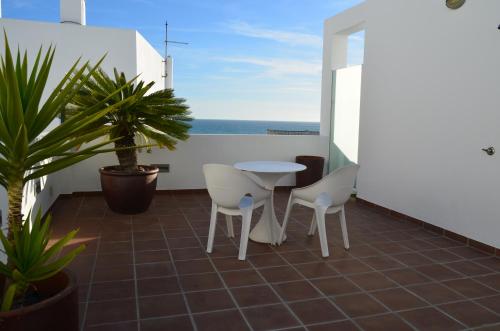 a balcony with a table and chairs and the ocean at Apartamentos El Arrecife in Conil de la Frontera
