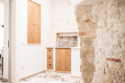 cocina con paredes blancas y pared de piedra en Trullo e Suites Parini 32, en Alberobello