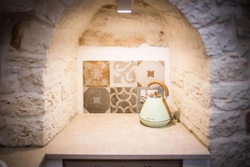 a kitchen with a stone wall with a tea kettle at Trullo e Suites Parini 32 in Alberobello
