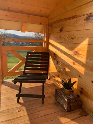 a wooden cabin with a bench sitting on a porch at Oaza mira, Kokin Brod in Nova Varoš