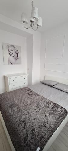 a white bedroom with a bed and a dresser at 44 - Apartamenty Siedlce - Nowy apartament w centrum przy ul Czerwonego Krzyża in Siedlce